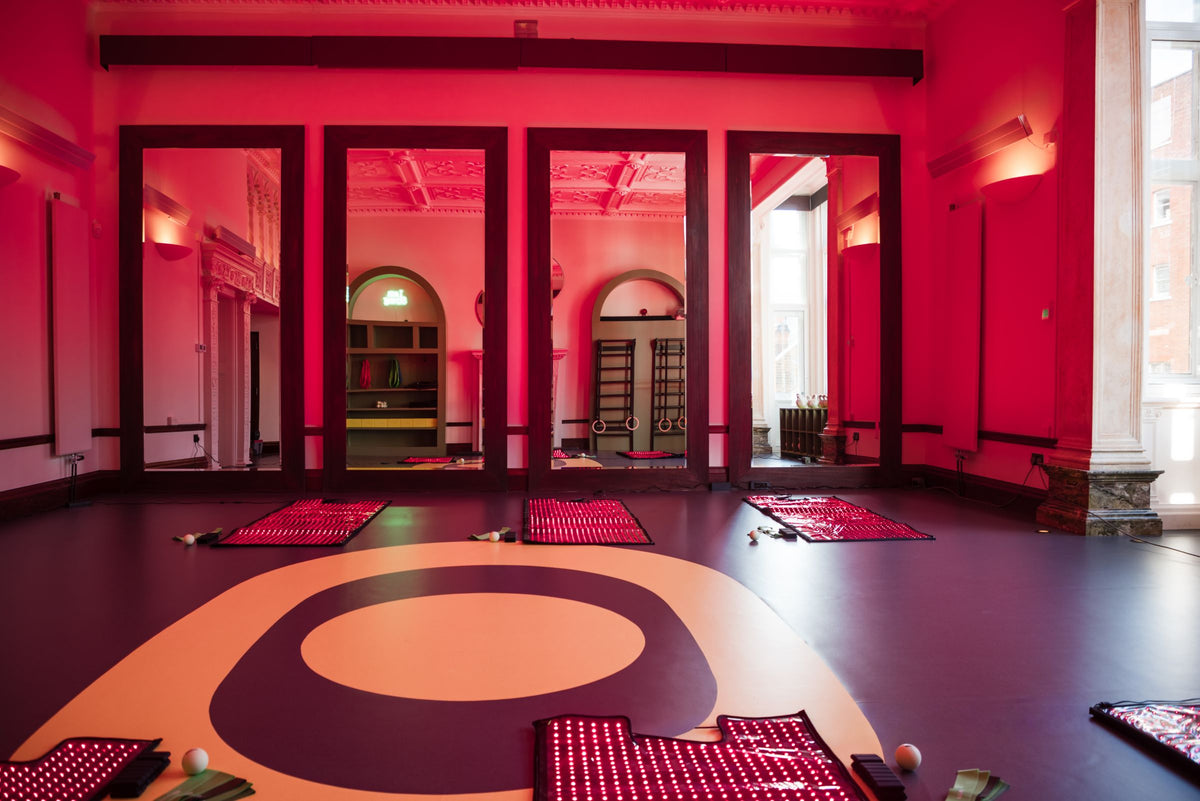 The eyeam world workout studio in red light, with heated mats laid out around the eyeam eye on the floor
