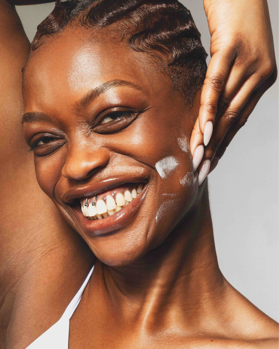Model smiling rubbing cream into her face.