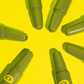 A yellow background highlighting a flower shape of green cream roller bottles.